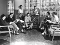 Circa 1950s photo of men and women in business attire sitting in a conference room